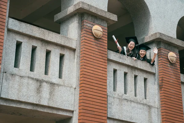 Students look down waving hand showing diploma — Stock Photo, Image