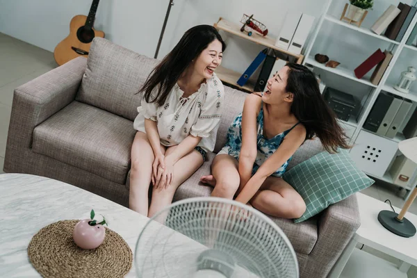 Friends sitting on couch cooling off with fan — Stock Fotó