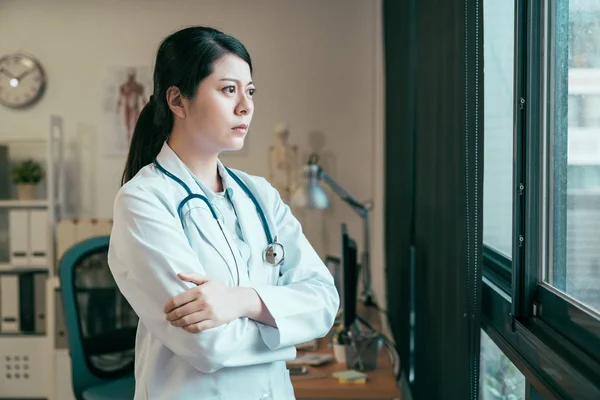 Medico guardare finestra e tenere le braccia incrociate — Foto Stock