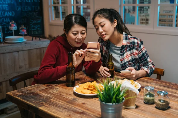 Happy women in pub pointing smart phone talking — Stock Photo, Image