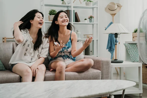 Niñas sosteniendo control remoto disfrutar de ventilador refrigerador de aire — Foto de Stock