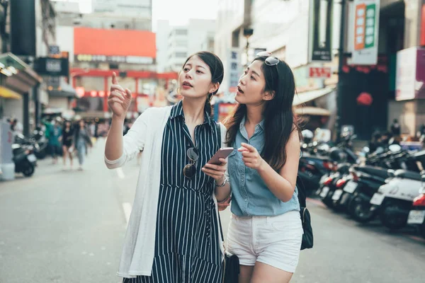 Girls holding cellphone point searching direction — Stock Photo, Image