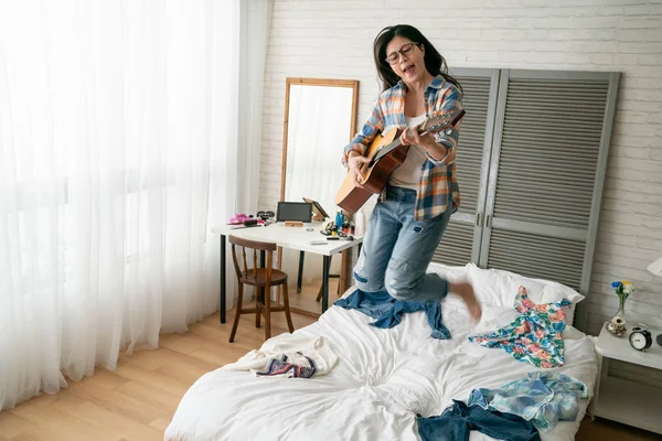 Mujer tocando la guitarra con felicidad saltar en la cama — Foto de Stock