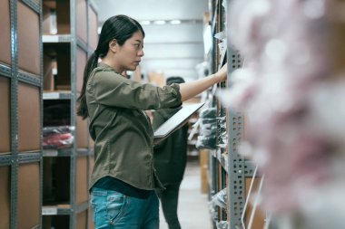 Kadın işçi depoda tablet kullanıyor.