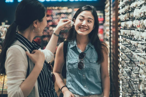 Pretty female friends trying pair of earrings — Stock Photo, Image