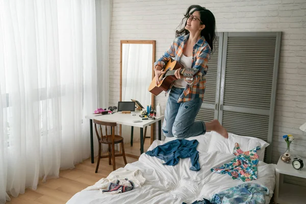 Chica divertida tocando guitarra divertirse bailando en la cama — Foto de Stock