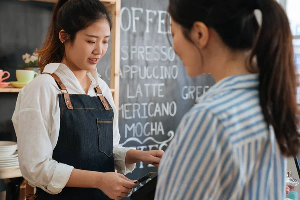 Barista femenina en delantal tomando tarjeta de crédito — Foto de Stock