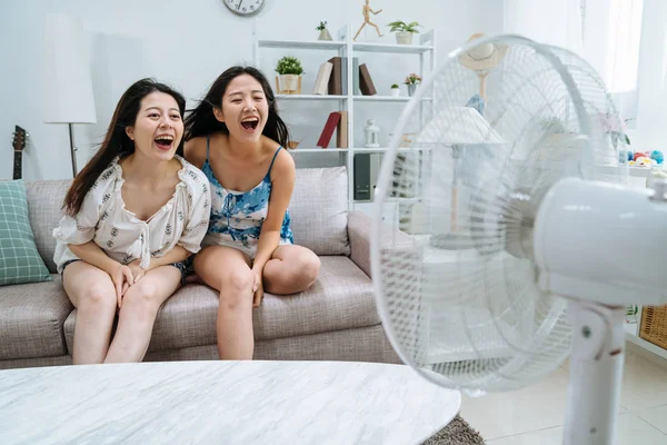 Vriend zittend op de Bank spelen met elektrische ventilator — Stockfoto