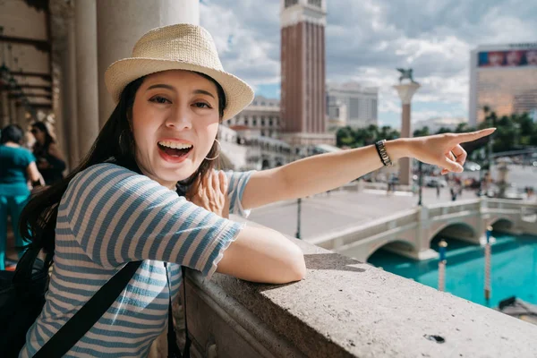 Sorridente ragazza backpacker faccia fotocamera mostrando vista — Foto Stock