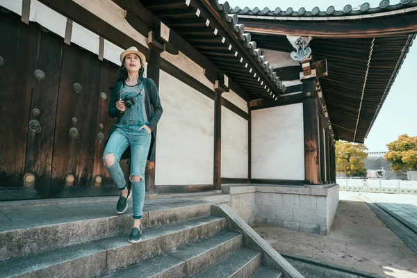 Женщина-путешественница с камерой спускается по лестнице — стоковое фото