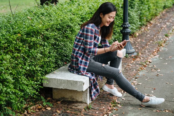 Menina feliz relaxar na cadeira de pedra por mensagens de texto prado — Fotografia de Stock