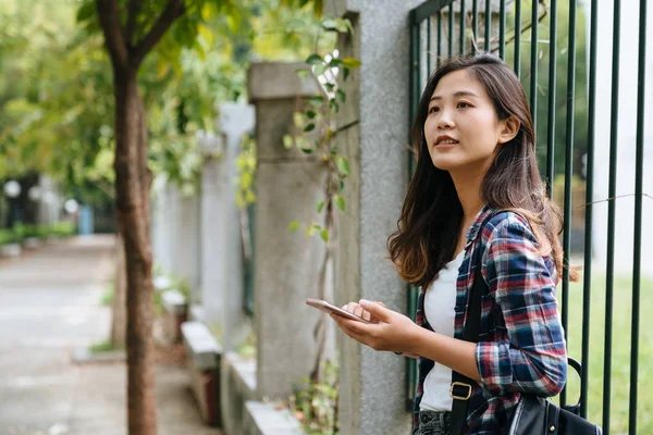 学校のフェンスの手すりに寄りかかっている女子大生 — ストック写真