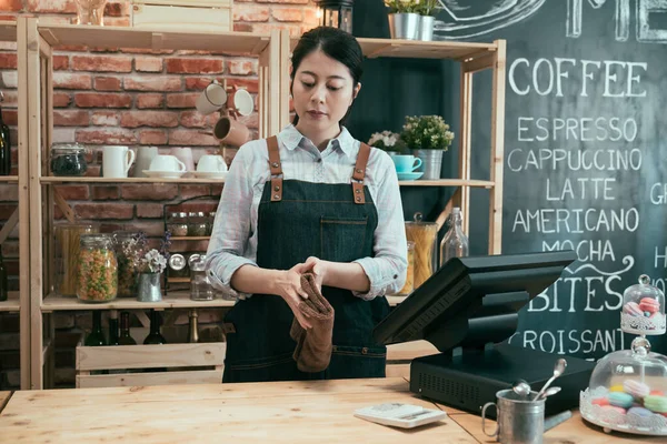 Waitress behind cafe counter using cloth wiping — Stock Photo, Image