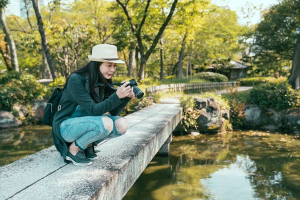 Flicka fotograf knäböja ner på sten bro — Stockfoto