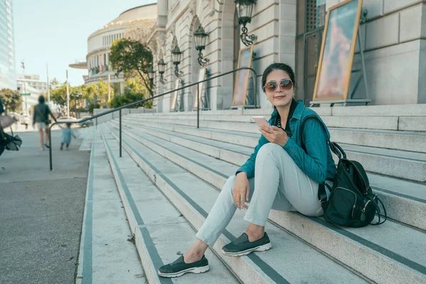 Woman sitting on stairs and using her smartphone — Stock Photo, Image