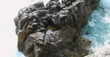Mavi deniz dalgaları beyaz köpük ve büyük kayanın üzerinde çökmesini hale getirir. Akdeniz'de Saint Jean Cap Ferrat, French Riviera, Fransa - 4 k Video