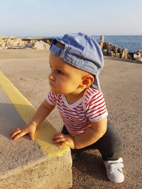 Şirin bebek çocuk 1 giyen A geriye doğru kap ve çizgili kıyafetler, yıl portre yakından. Akdeniz içinde belgili tanımlık geçmiş