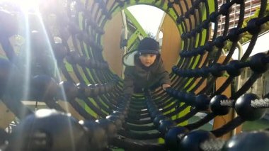 Şirin bebek çocuk bir halat tünel köprü bir oyun alanı üzerinde sürünerek. Görünümü - 4 k çözünürlüklü kapatın