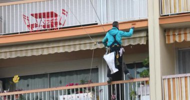 Roquebrune-Cap-Martin, Fransa-8 Ocak 2019: Adam bir ip, endüstriyel dağcı (Restoratör) aşağı, Closeup görünümü - Dci 4 k Video olacak bina, duvar boyama tutunarak