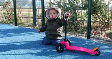 Şirin bebek çocuk bir 3 tekerlekli Scooter ile oyun alanı üzerinde oynama. Kadar görünüm portre - Dci 4 k çözünürlüklü kapatın