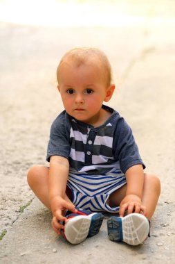 Sokakta yerde oturan erkek bebek