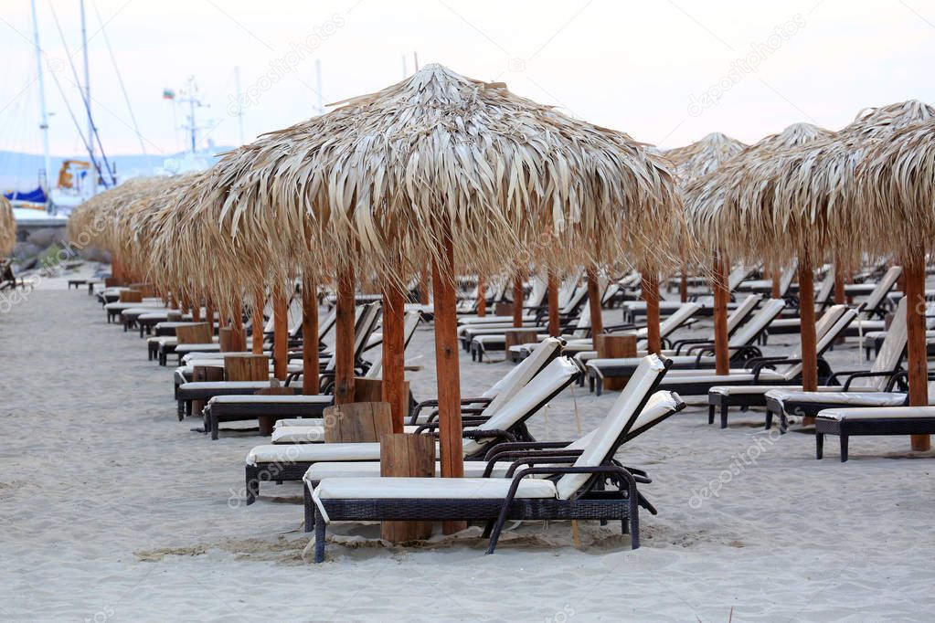 Sea Sand Beach With Wooden Sun Loungers And Straw Umbrellas