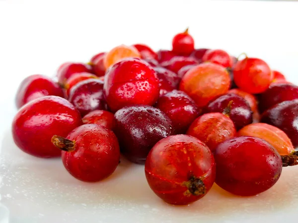 Gooseberries and wild cherry berries (gean) on a light background