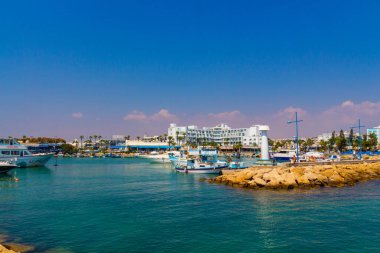 Ayia Napa, Kıbrıs - 06 Eylül 2019: Ayia Napa Limanı. Balıkçı tekneleri, palmiyeler ve turistler.