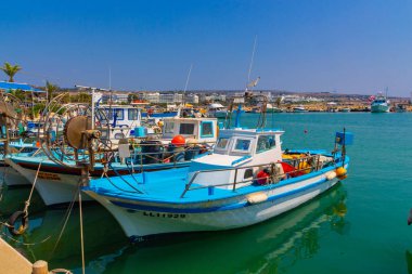Ayia Napa, Kıbrıs - 06 Eylül 2019: Ayia Napa Limanı. Balıkçı tekneleri, palmiyeler ve turistler.