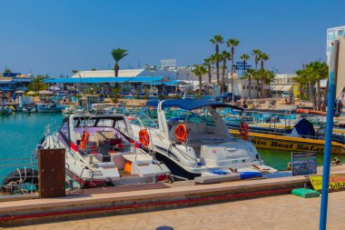 Ayia Napa, Kıbrıs - 07 Eylül 2019: Ayia Napa Limanı. Balıkçı tekneleri, palmiyeler ve turistler.