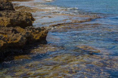 Kayalık bir sahilde şeffaf deniz dalgaları. Protaras, Kıbrıs. Protaras ağırlıklı olarak turizm merkezidir..