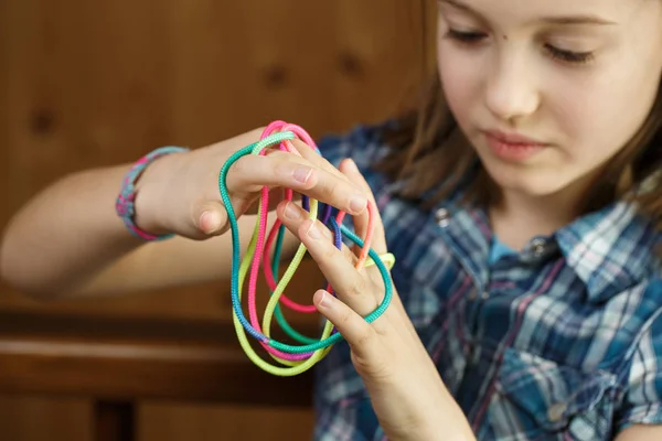 女孩玩经典的 老派的弦乐游戏和教条玩具与她的手指 创造形状 发展她的运动技能 乐趣和童年概念 — 图库照片