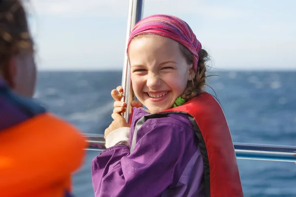 Smiling girl in safety jacket on a boat trip. Family on a blue whale watching trip.