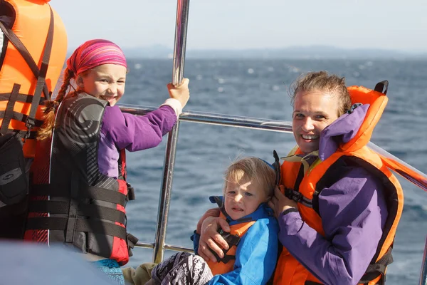 Family on a blue whale watching trip. Smiling girl in safety jacket on a boat trip. Mother holding baby