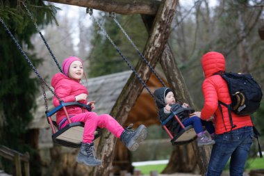 Küçük kardeşim ve kız kardeşi salıncakta anneleri ile kaliteli zaman geçirmek. Özgürlük, kavramı açık vakit çocukluk,. 