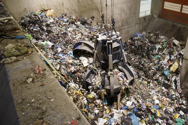 Mechanical claw hand grabbing pile of mixed waste