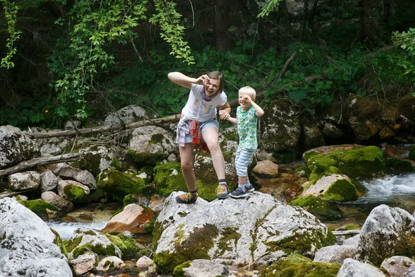Anya a fiával, hogy vicces arcok, szórakozás mellett egy hegyi patak-ra egy család utazás. — Stock Fotó