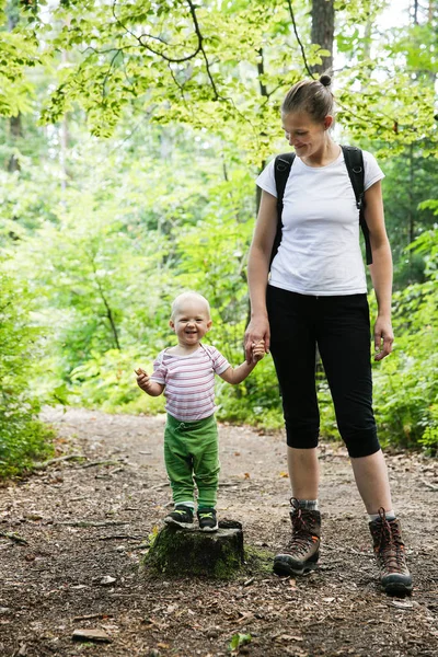 Toegewijde moeder hand in hand met haar zoon, wandelen in het bos. — Stockfoto