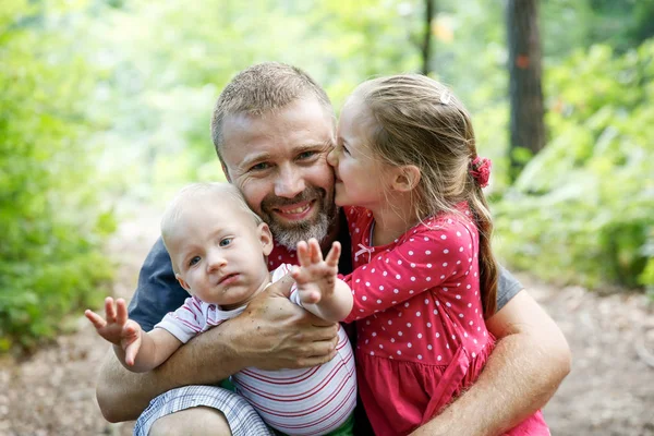 Père dévoué étreignant son fils et sa fille, profitant du plein air . — Photo