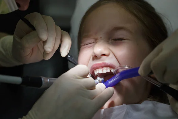 Niña asustada en el consultorio de dentistas, con dolor durante un tratamiento . —  Fotos de Stock