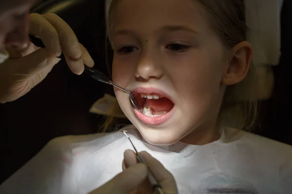 Испуганная маленькая девочка в кабинете дантиста, испытывающая боль во время лечения . — стоковое фото