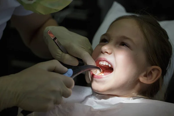 Uśmiechnięta dziewczynka w gabinecie stomatologicznym, coraz zęby sprawdzane przez stomatologa. — Zdjęcie stockowe