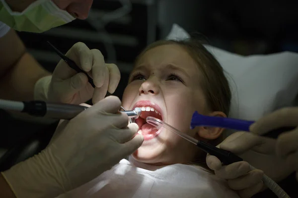 Niña asustada en el consultorio de dentistas, con dolor durante un tratamiento . — Foto de Stock