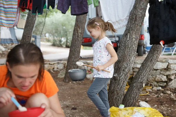 Girl at the campsite, cooking food in outdoor kitchen, having fun in the outdoors, mother eating. — Stock Photo, Image