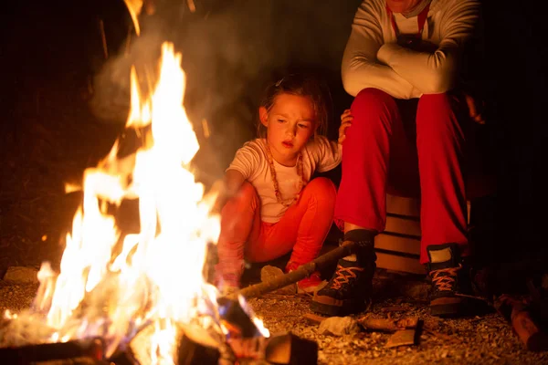 Mother and daughter spending quality time by a self-made campfire during adventurous camping trip, playing with fire. — Stock Photo, Image