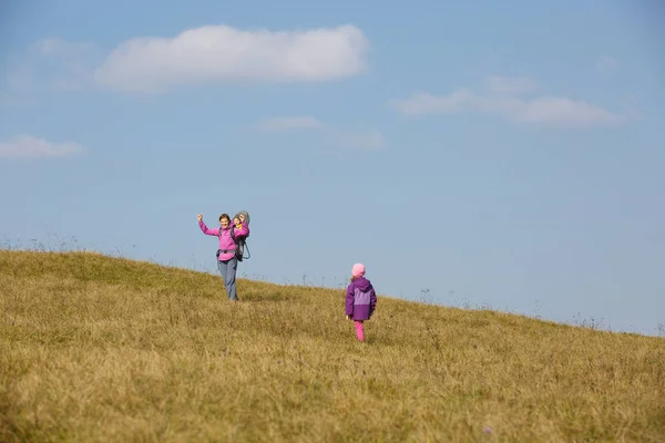 Madre con niños senderismo en un bonito día de otoño llevando niño — Foto de Stock