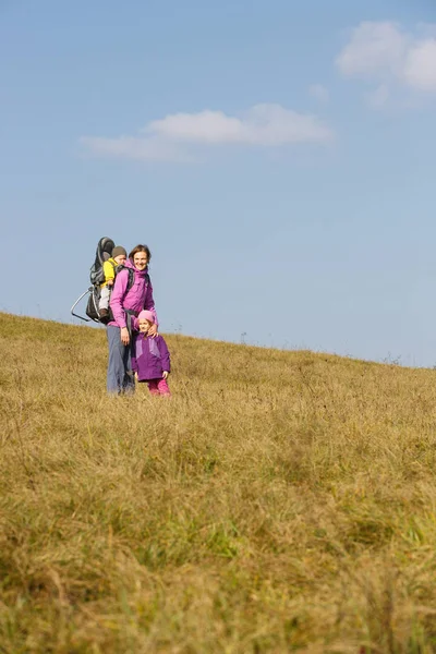 Madre con niños senderismo en un bonito día de otoño llevando niño — Foto de Stock