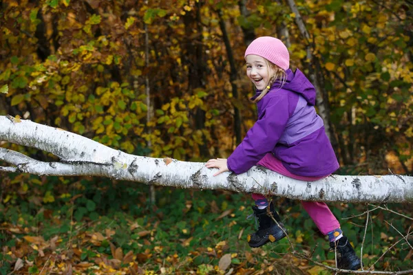 Lány játszik erdőben, ül egy nyírfa napló — Stock Fotó