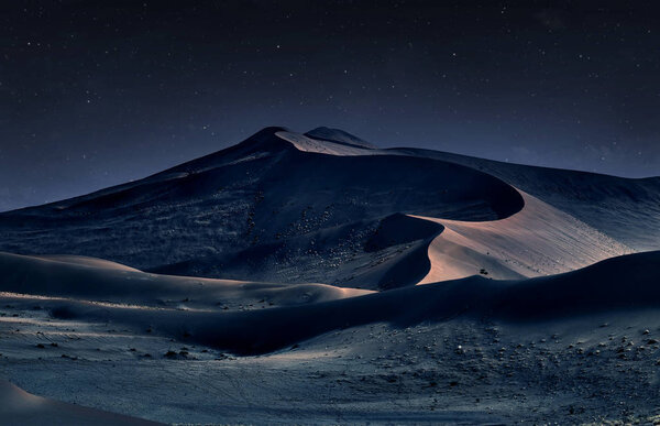 desert of namib at night with orange sand dunes and starry sky