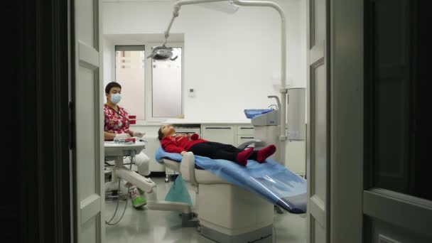 Стоматолог оглядає зуби маленької дівчинки — стокове відео